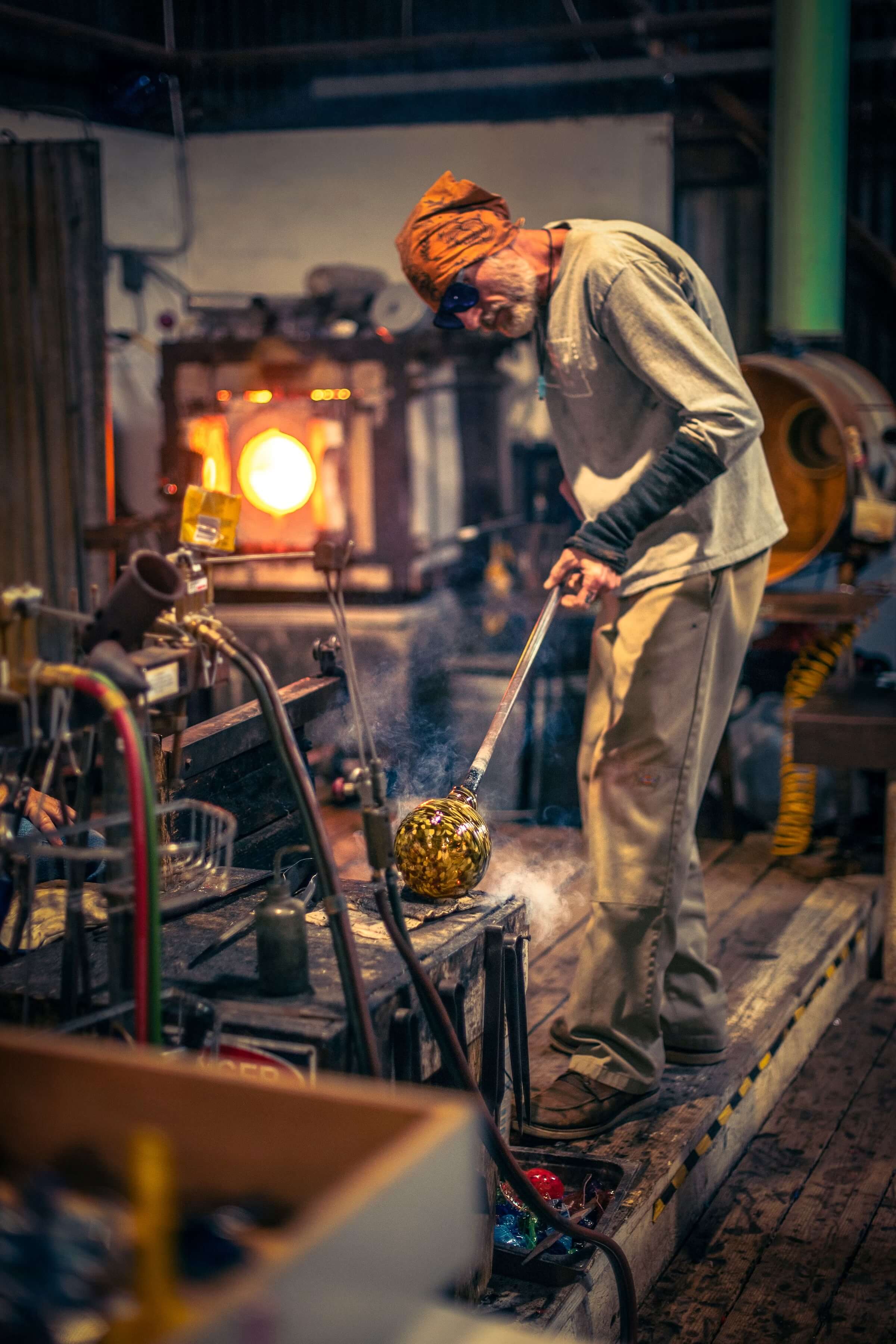 Glassblower working with molten glass at a furnace
